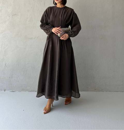 Woman wearing chocolate brown pleated maxi dress with long sleeves